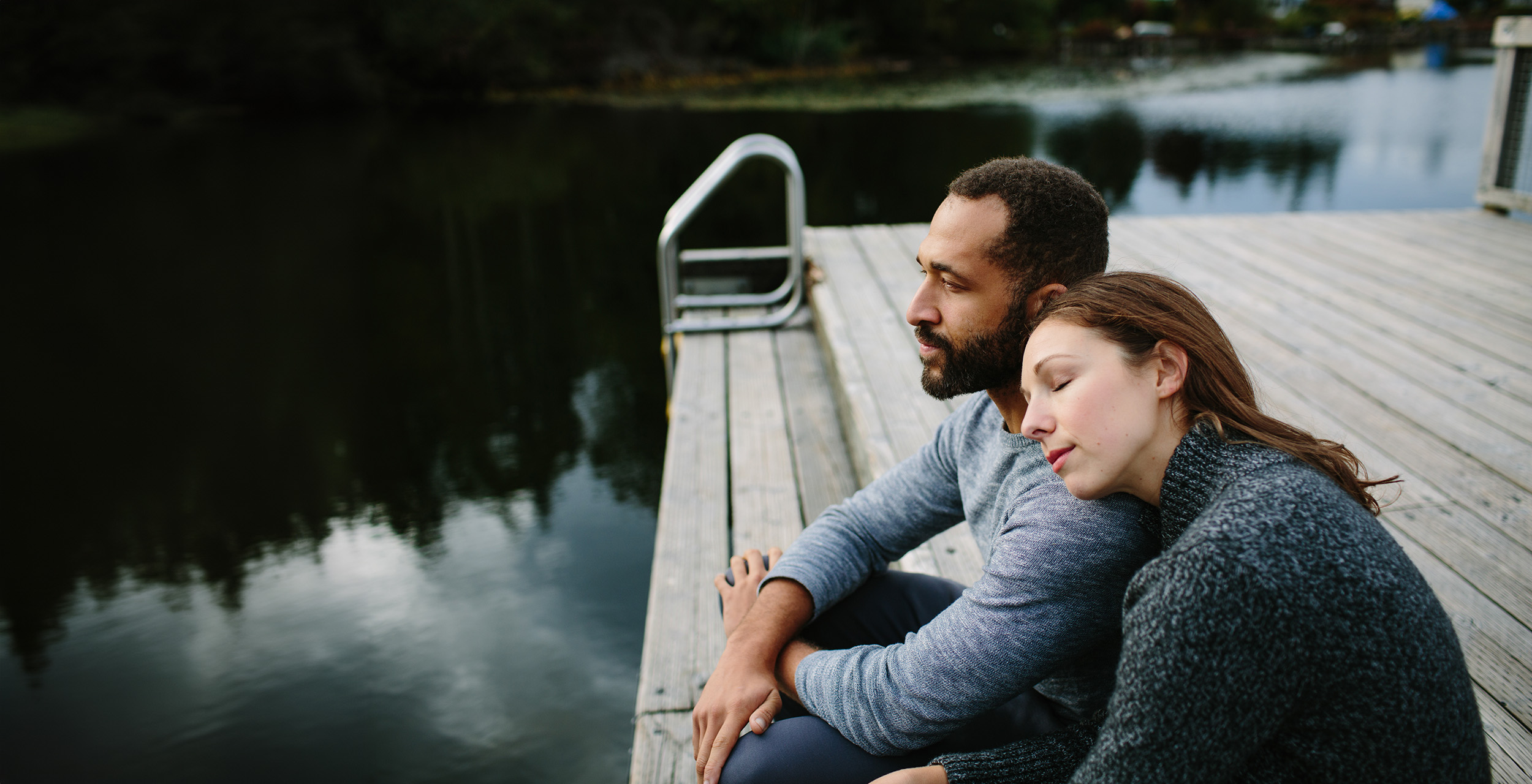 Couple sitting together by a lake Couple sitting together by a lake